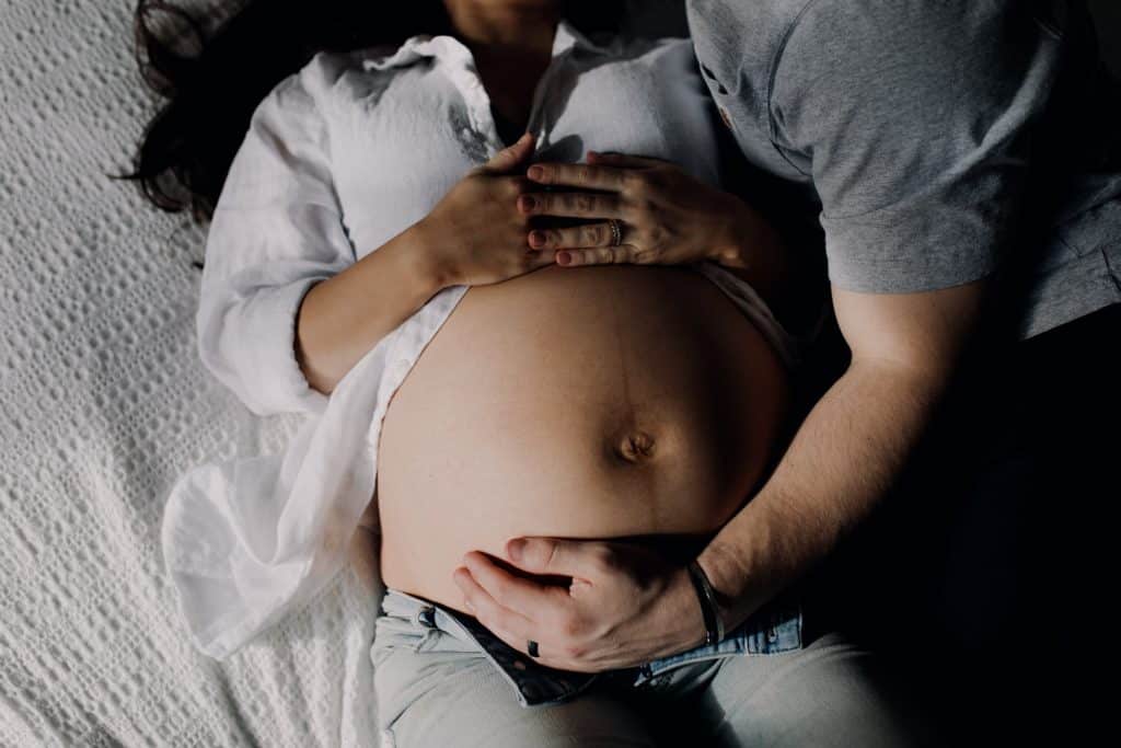 expecting parents are laying on bed and cuddling baby bump. Hampshire maternity photography. Hampshire maternity photographer. Maternity photo session. Ewa Jones Photography