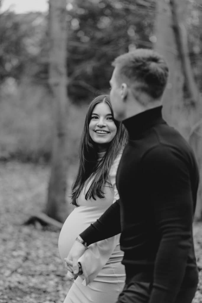 expected mum is looking at her husband and smiling. outdoor maternity photo session in Hampshire. Hampshire photographer. Ewa Jones Photography