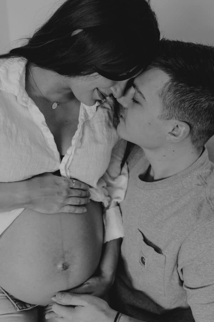 Black and white image of mum and dad cuddling close. Mum is expecting baby. intimate in home maternity photo session. Maternity photographer in Hampshire. Basingstoke photographer. Ewa Jones Photography