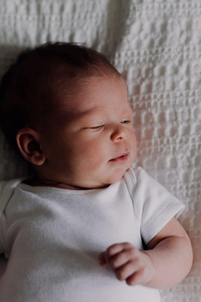newborn baby is laying on bed and looking away. newborn photo session at home. Hampshire newborn photographer. Hampshire newborn photography. Ewa Jones Photography
