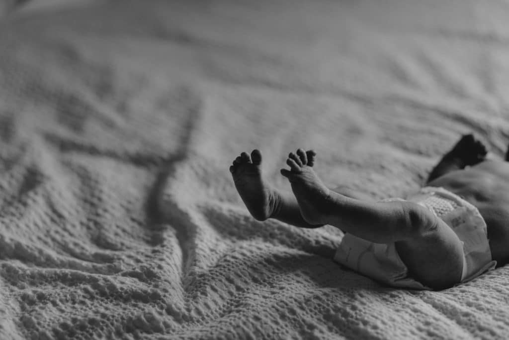 newborn baby toes. black and white image of baby laying on bed. candid newborn photo session at home. Newborn photographer in Hampshire. Ewa Jones Photography