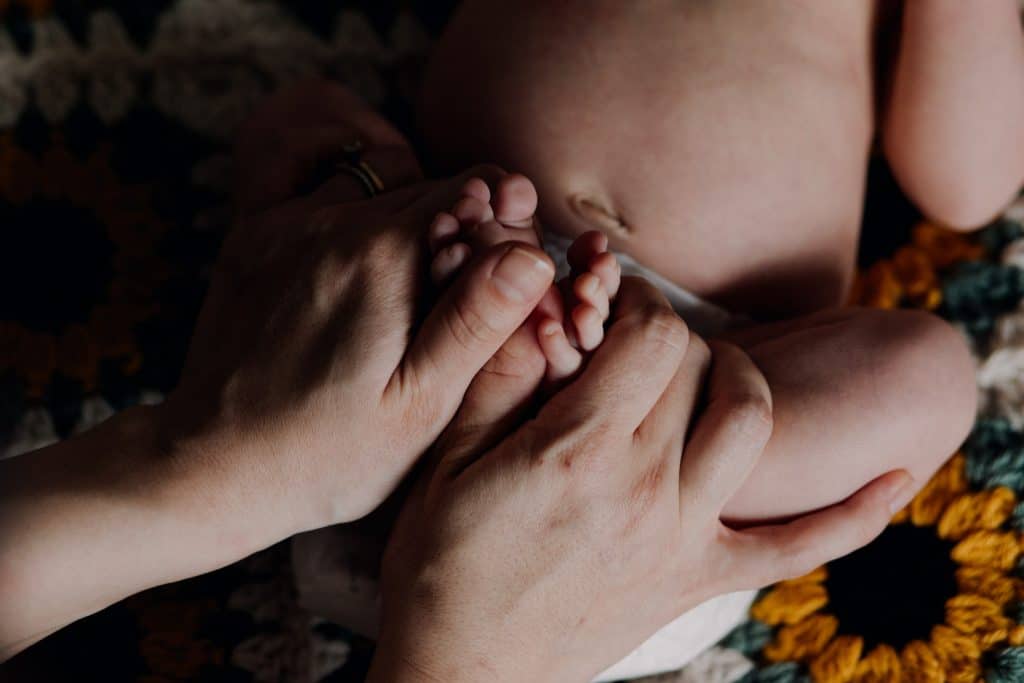 mum is holding newborn baby feet. in home newborn photo session. Basingstoke newborn photographer. Ewa Jones Photography