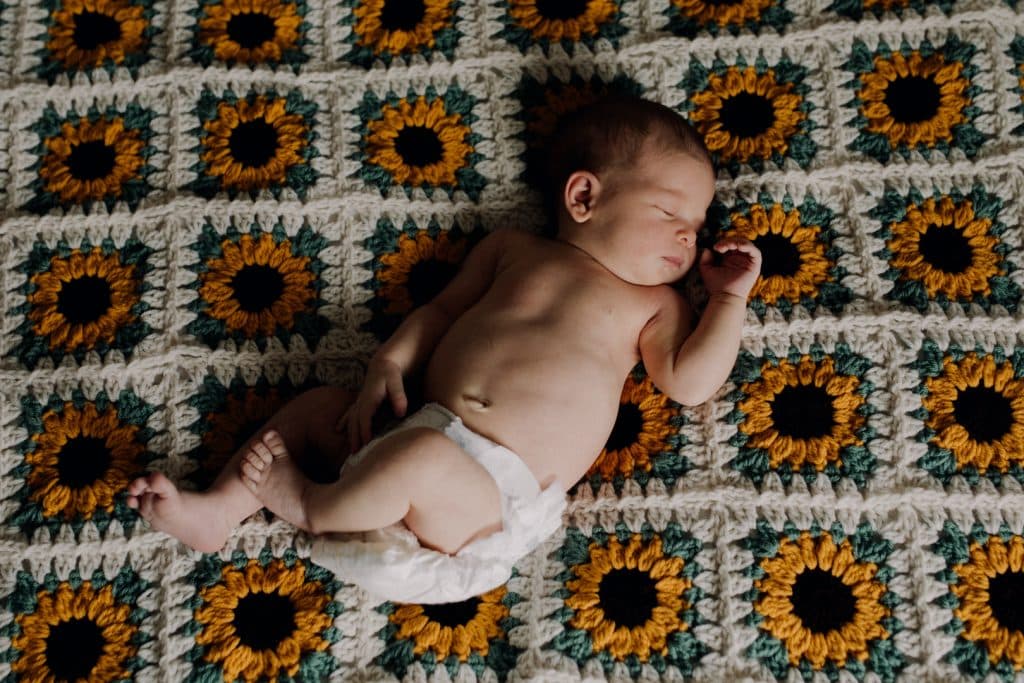 Newborn baby is laying on sunflower blanket. Lovely natural newborn photo shoot at home. Hampshire photo session. Hampshire newborn photographer. Ewa Jones Photography