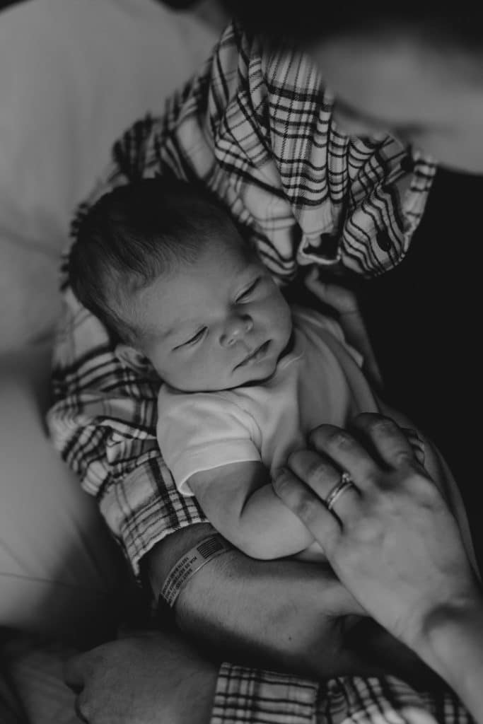 newborn baby is being held by daddy. black and white newborn image. newborn photo session at home. Hampshire newborn photo shoot. Hampshire newborn photographer. Ewa Jones Photography