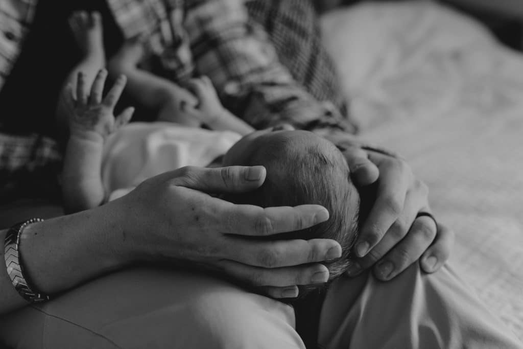 black and white image of close up of newborn baby's head being held by mummy and daddy. newborn photo session in Hampshire. Newborn photo shoot at home. Ewa Jones Photography