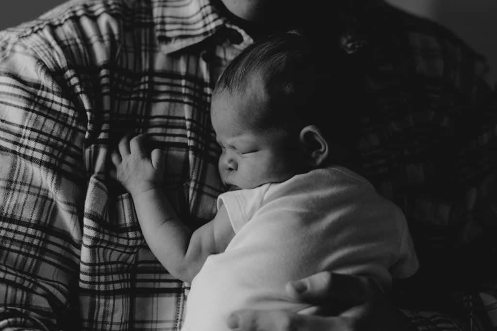 newborn baby is cuddling to dad. intimate newborn photoshoot at home. Hampshire newborn photo session. Newborn photo session in Hampshire. Ewa Jones Photography