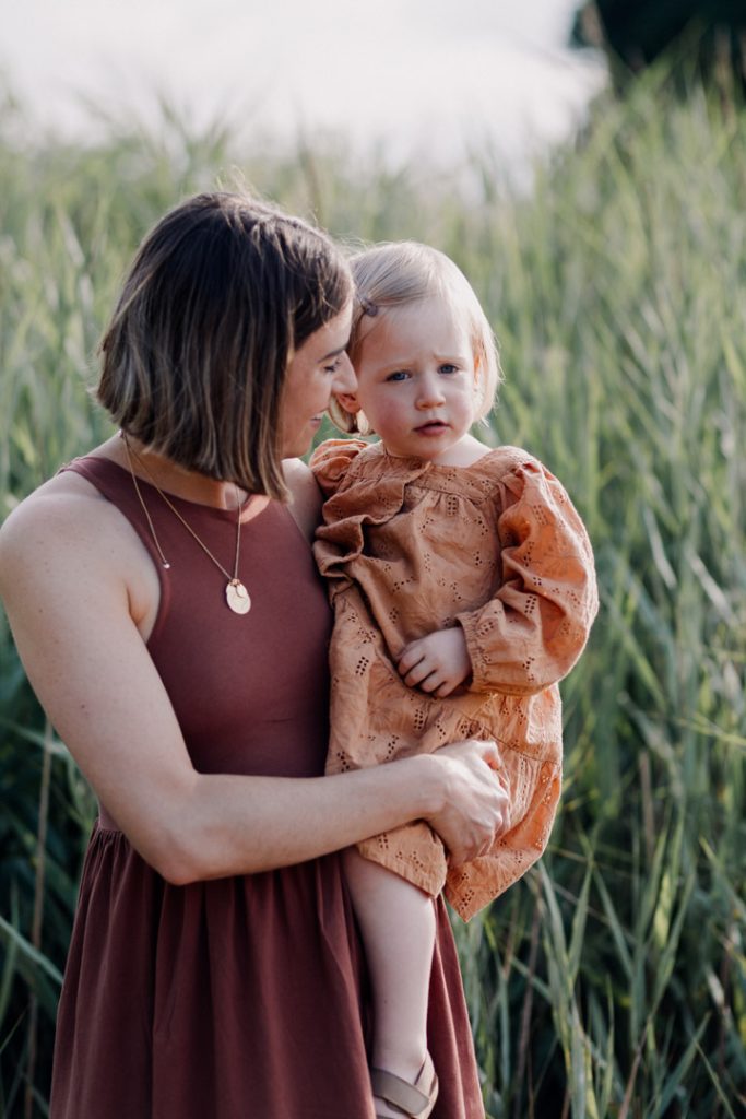 mum is holding her daughter and looking at her. family photo shoot. Outdoor session in the sun. Ewa Jones Photography
