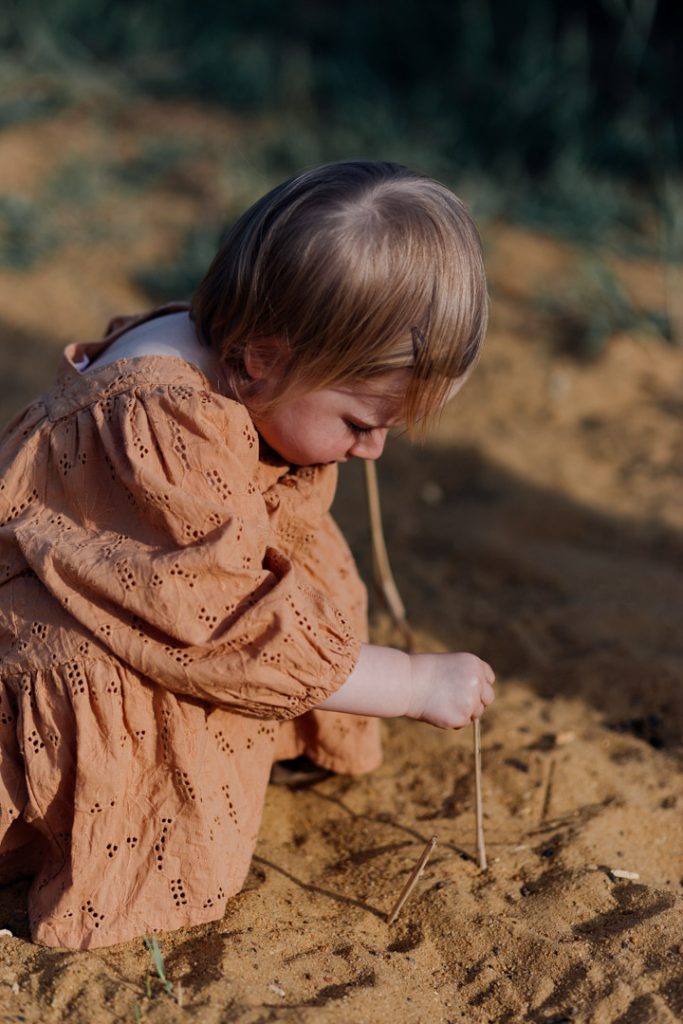 girl is playing in the sand. natural outdoor family session capturing every day life. Ewa Jones Photography