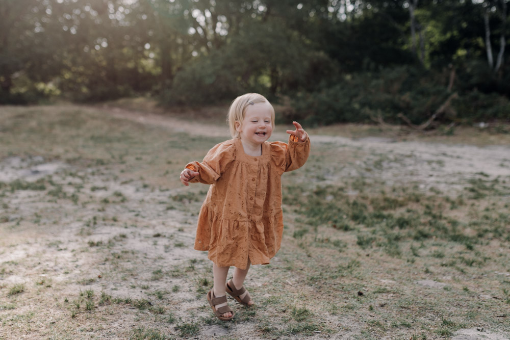 little girl is jumping and smiling. She is wearing lovely dress. What to wear for a family session. Hampshire photo shoot. Ewa Jones Photography
