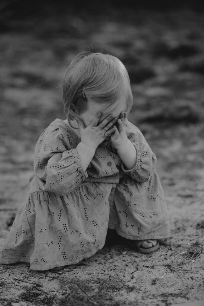 little girl is playing peek-a-boo. natural session outdoors. Hampshire photo shoot. Ewa Jones Photography