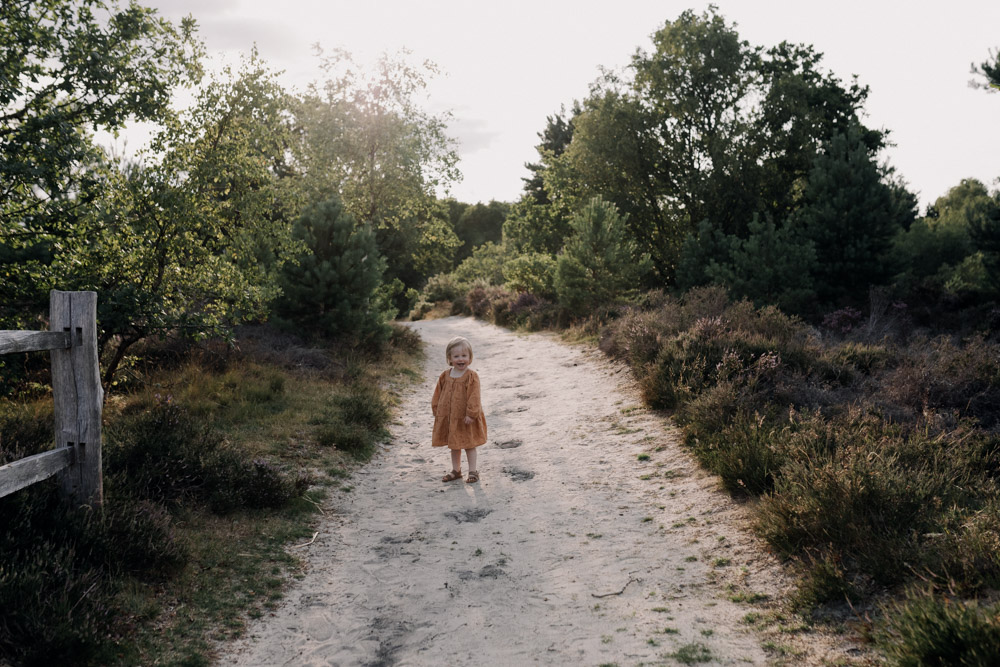 little girl is standing and looking and smiling at the camera. family photographer in Hampshire. Ewa Jones Photography