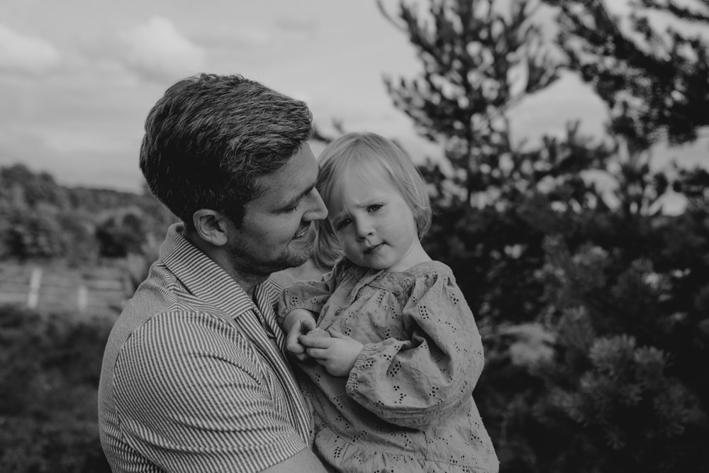 little girl is looking at the camera and dad is holding her. Hampshire photo shoot. Ewa Jones Photography