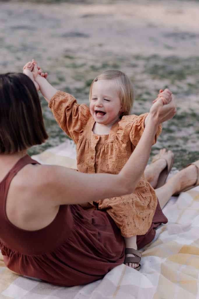 mum is looking at her daughter and they are playing row row the boat. Family photo session outside. Hampshire family photographer. Ewa Jones Photography