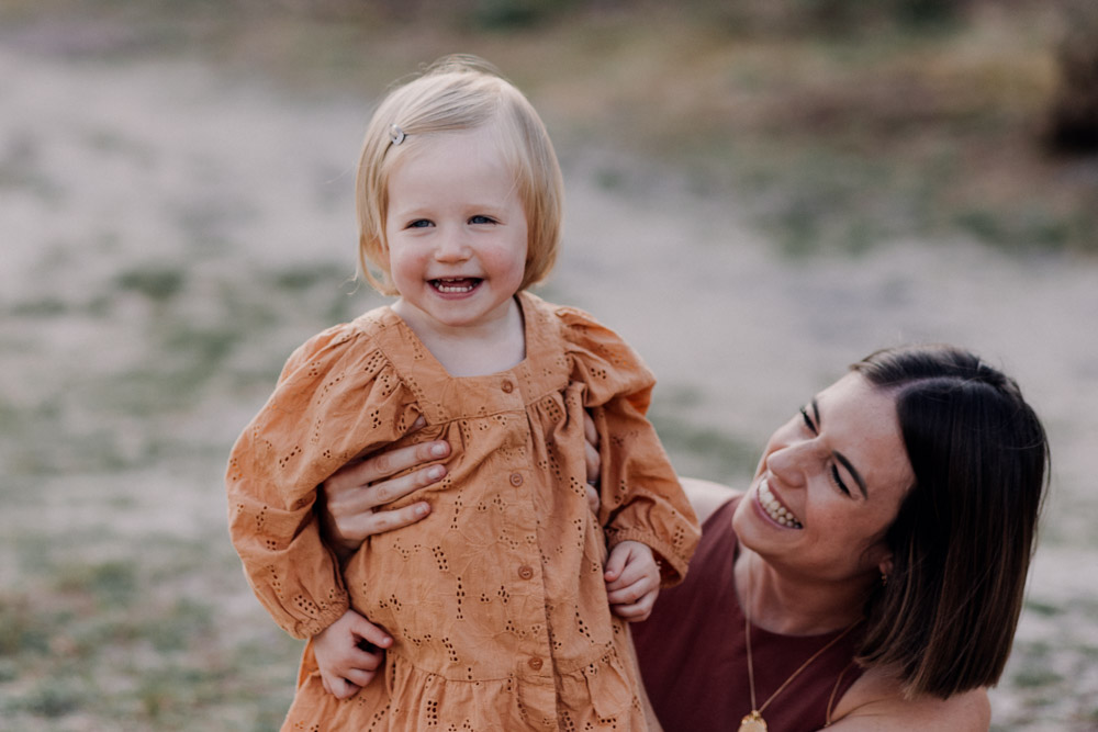 little girl is laughing and looking at the camera. happy family session outdoors. Ewa Jones Photography