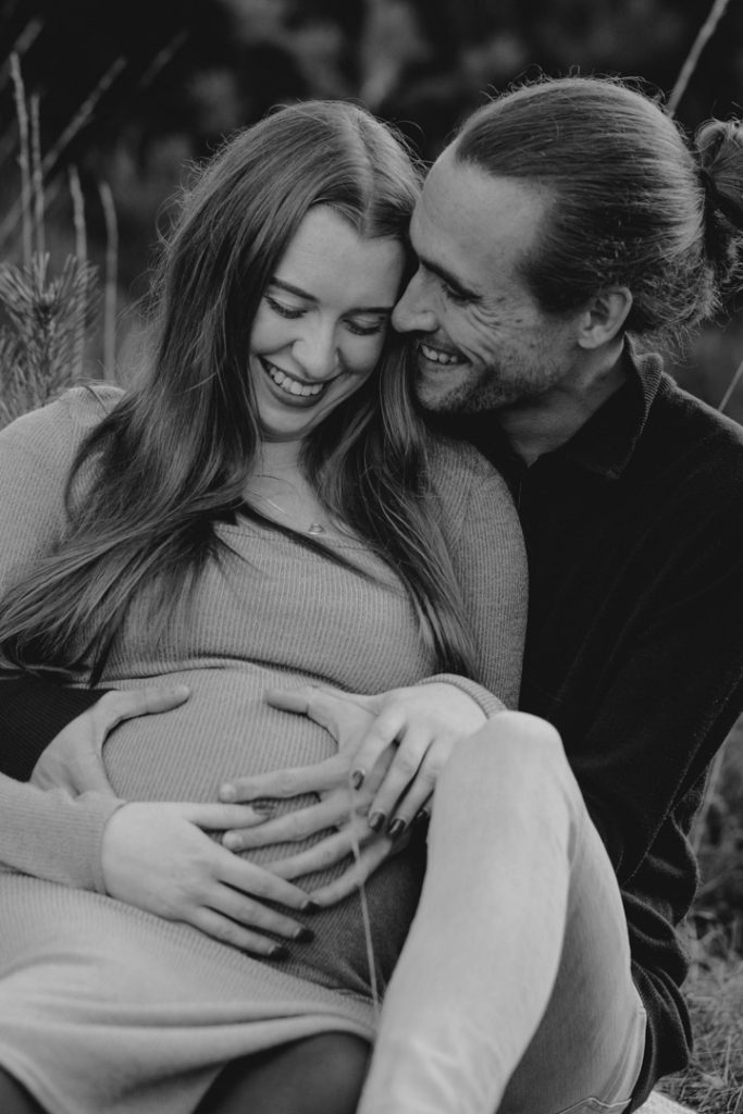 Maternity photo session in Basingstoke 06.12.24-10 expecting parents are sitting on the blanket and laughing. Maternity photo session outside. Hampshire maternity photo shoot. Ewa Jones Photography