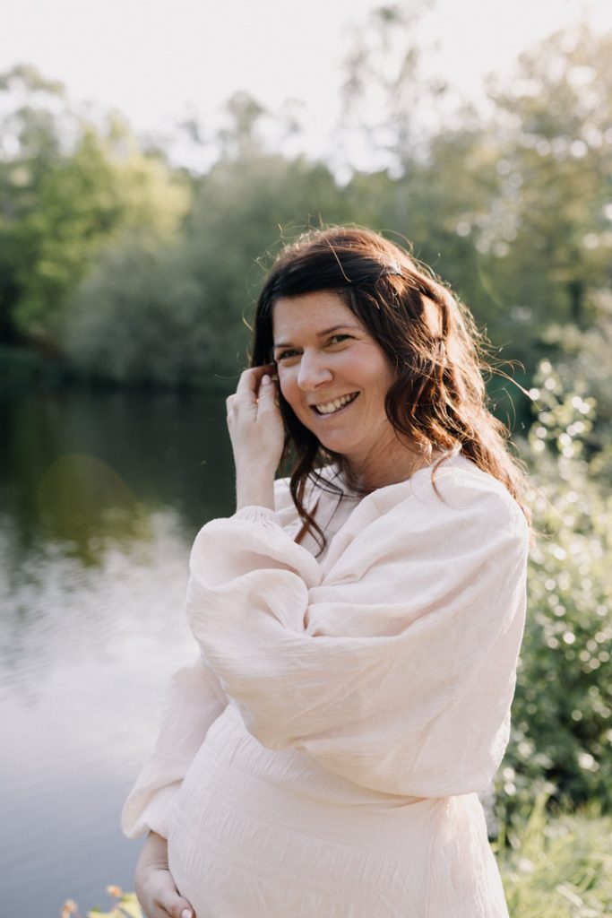 mum is standing and smiling. She is wearing lovely maternity dress. Outdoor maternity session. Ewa Jones Photography
