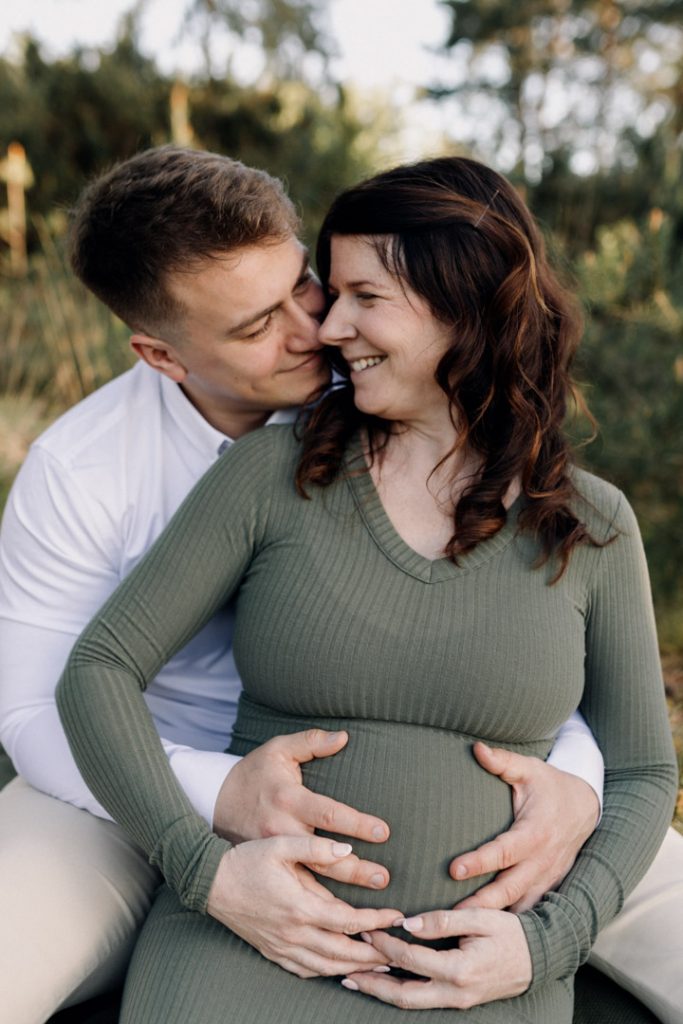 Mum and dad are smiling and sitting on the blanket. outdoor maternity session in Hampshire. Hampshire maternity photographer. Ewa Jones Photography
