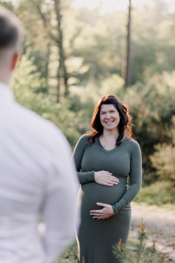 Lovely mum to be is looking at her partner. mum to be is wearing lovely green dress. Maternity session. Ewa Jones Photography