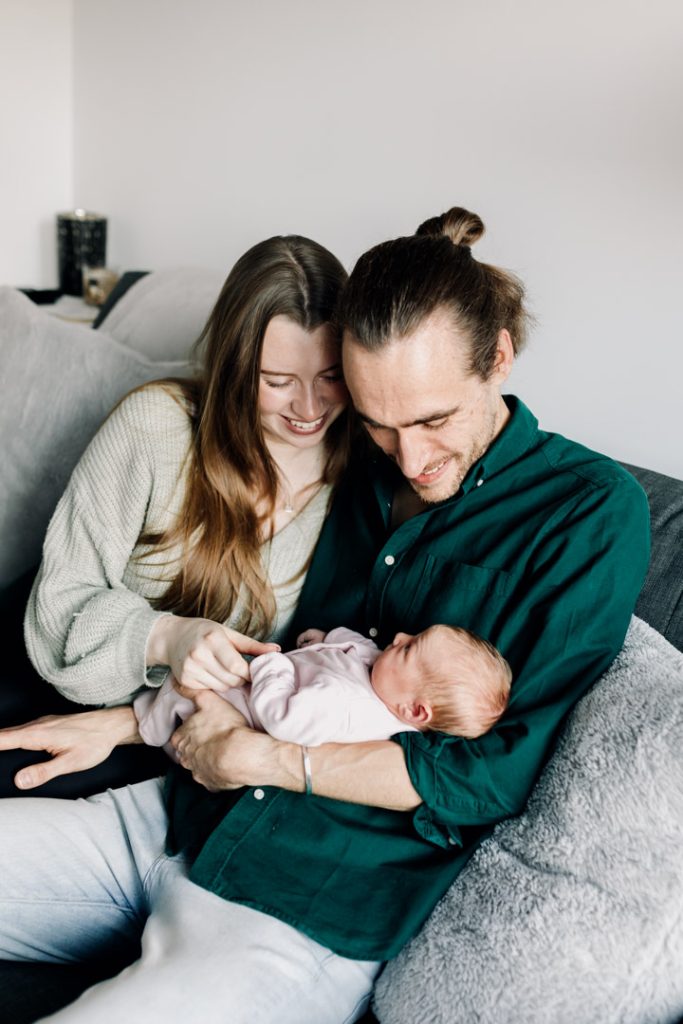 Newborn photo session in Basingstoke 19.01.24-1 mum and dad are cuddling newborn baby and looking down at baby. Newborn photo shoot at home. Ewa Jones Photography
