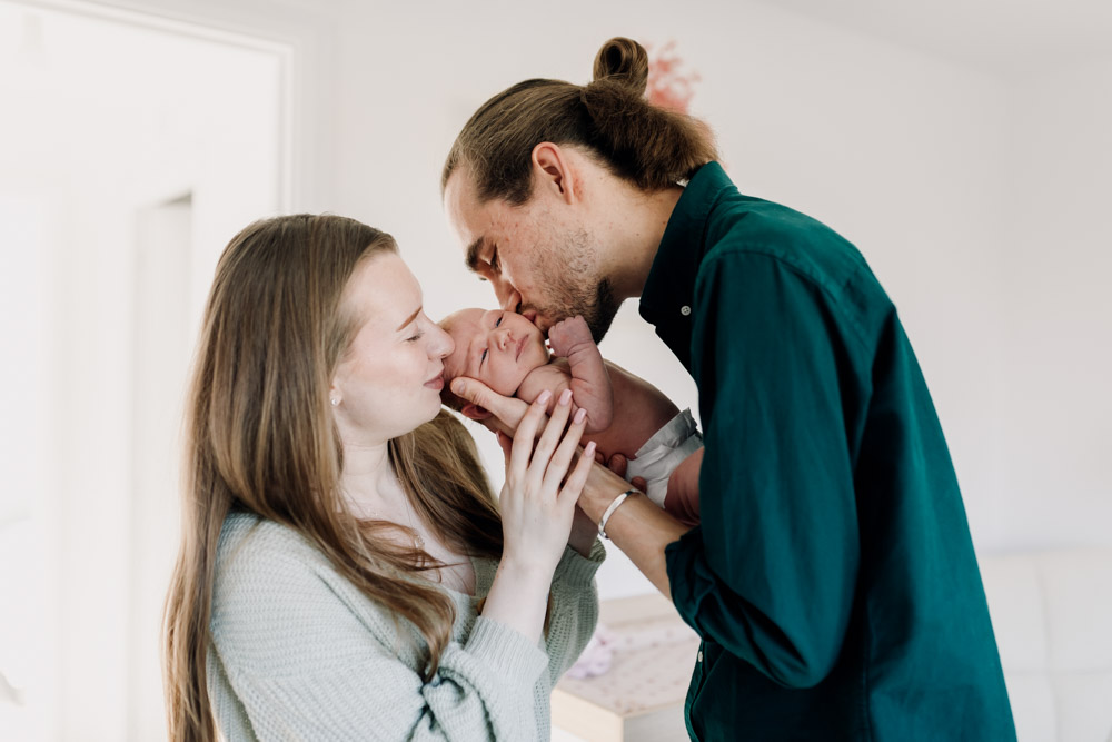 Newborn photo session in Basingstoke 19.01.24-4 mum and dad are kissing newborn baby. Hampshire newborn photo session. Ewa Jones Photography