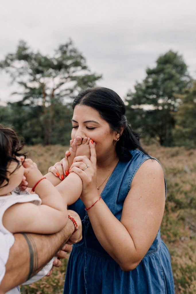 Mum is kissing little boy feet. Outdoor family session. Celebrating one year old birthday. Photo shoot in Surrey. Ewa Jones Photographer