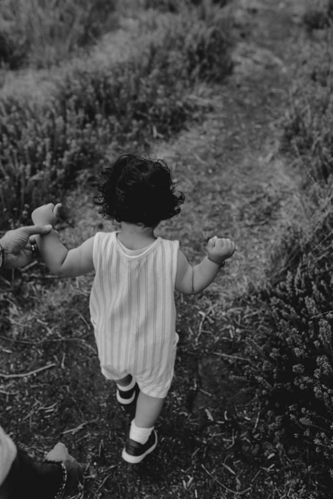 Black and white image of little boy walking. Natural unposed family photo session. Ewa Jones Photography