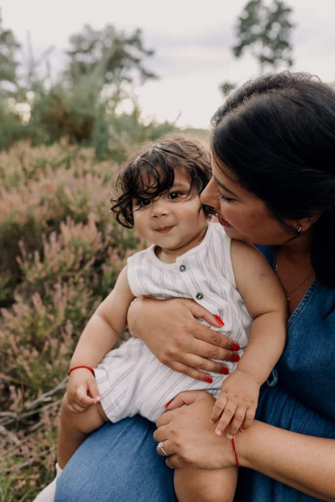 Little boy is sitting on mums lap and smiling. Lovely family photo shoot outside. Family session. Family photographer. Ewa Jones Photography