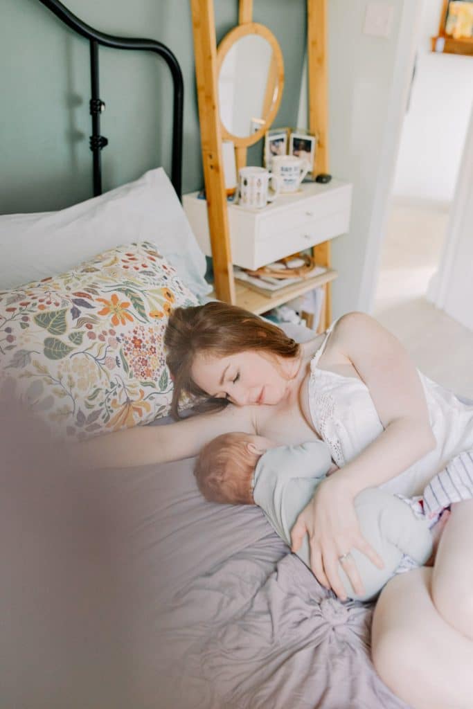Mum is breastfeeding her baby boy and laying on a bed. The Magic of Intimate In-Home Newborn Photo Session. Newborn photographer. Ewa Jones Photographer