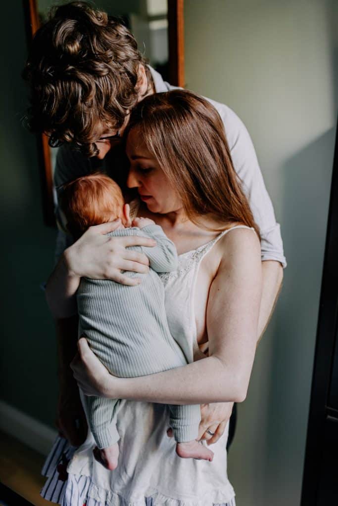 Mum and dad are cuddling close. Newborn photo session. In home newborn photography. Ewa Jones Photographer