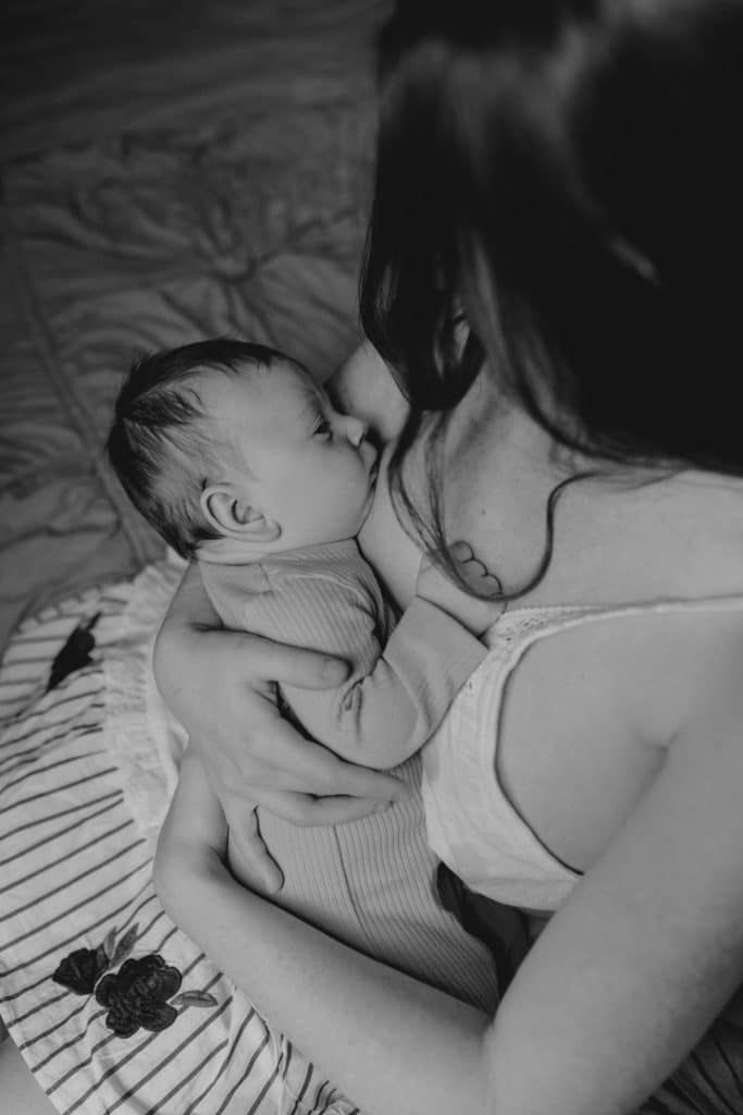 baby boy is being held by his mum. Mum is sitting on the bed. Newborn session. Newborn photographer. Hampshire photographer. Ewa Jones Photographer