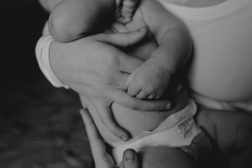 Close up image of baby hand holding mumy hand. Black and white image. Newborn photo session. Hampshire photo shoot at home. Newborn photographer. Ewa Jones Photography