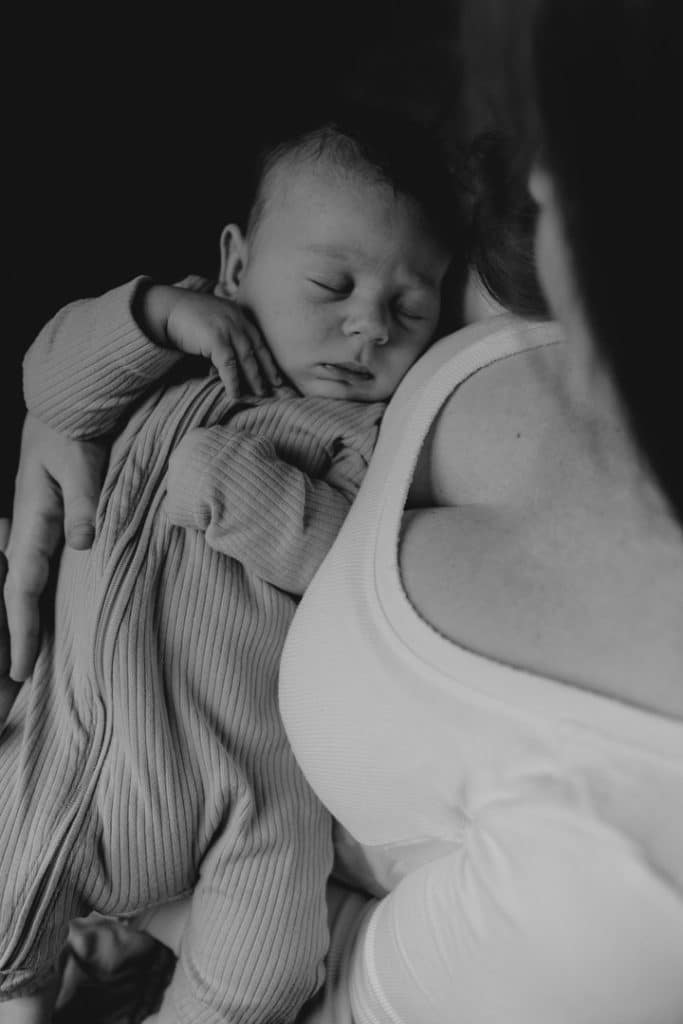 Mum is holding baby boy in her arms. Baby boy is sleeping in mums arms. Hampshire photo session. Hampshire newborn photographer. Ewa Jones Photography