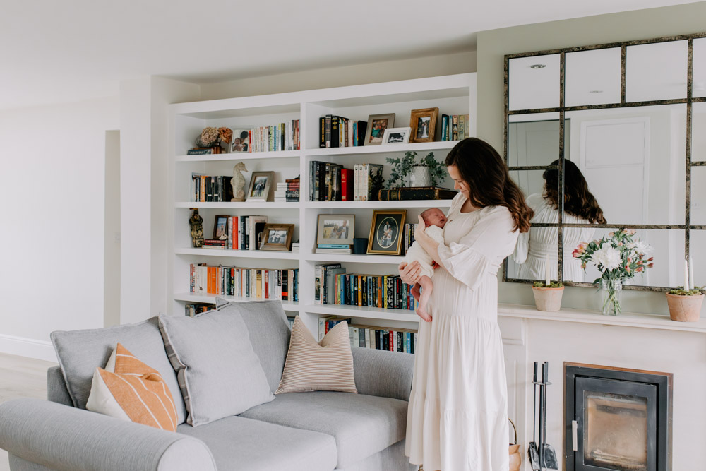Mum is standing in the living room and holding newborn baby. Newborn photography at home. Hampshire photographer.