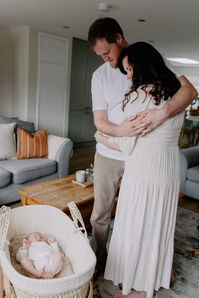Mum and dad are cuddling and looking at their baby boy. Lovely natural lifestyle newborn session in Hampshire. Ewa Jones Photography