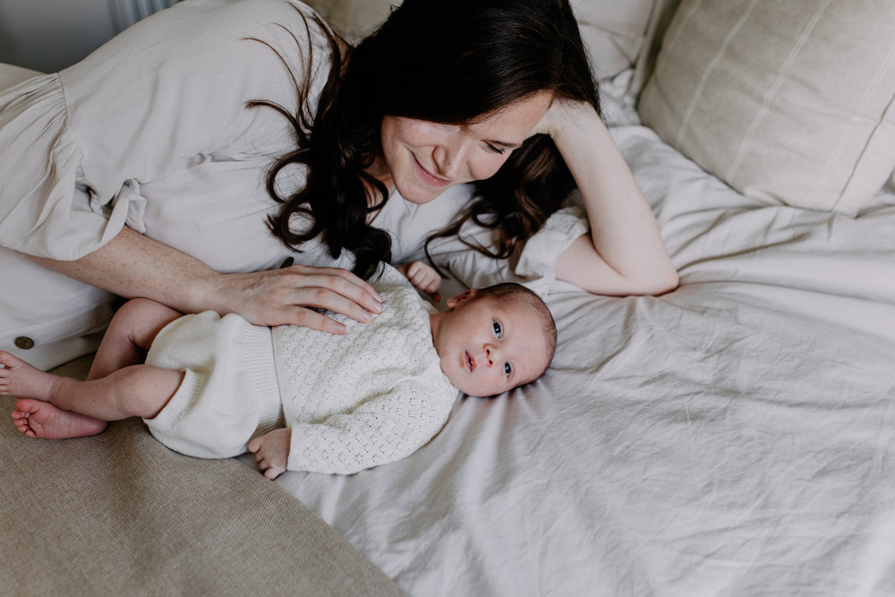 Mum is laying on the side and looking at her newborn baby. Hampshire newborn photographer. Ewa jones Photography
