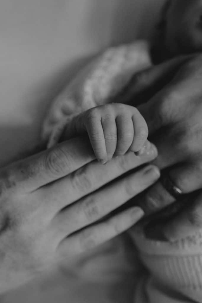 Black and white close up of baby's hand and mums hand. lovely detail during newborn photo session. Newborn photography in Hampshire. Ewa Jones photography