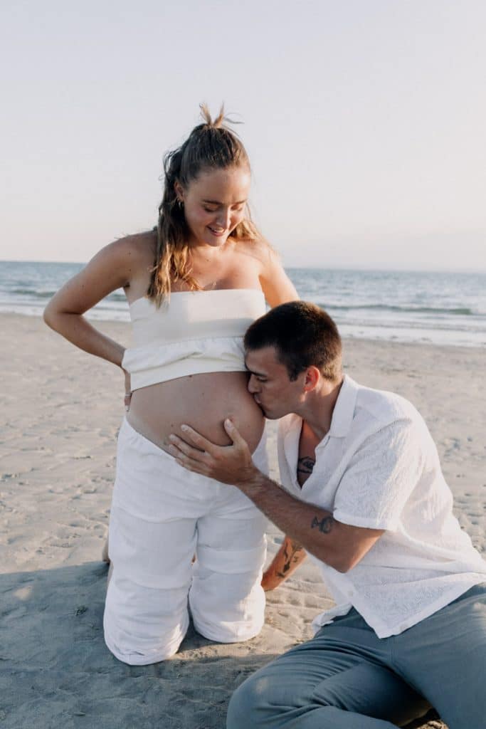 Dad to be is kissing baby bump. Beach baby bump photo shoot. Maternity photo session at the beach. Hampshire maternity photographer. Ewa Jones Photography