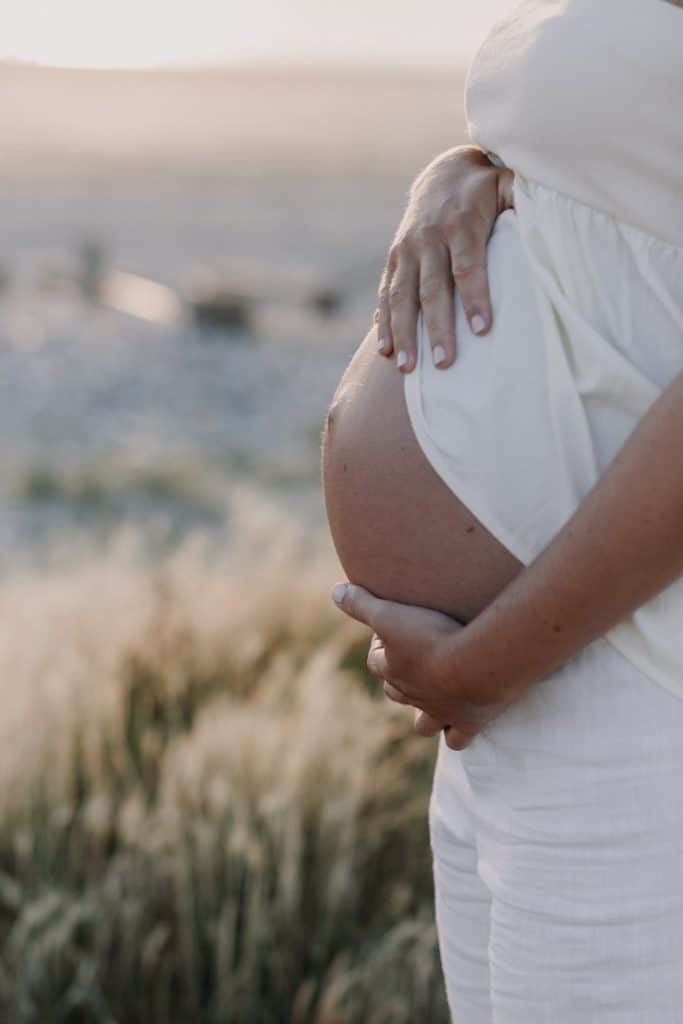Close up bump image. Mum is gently touching her baby bump. Sunset maternity photo shoot. Beach photo session. Hampshire maternity photographer. Ewa Jones Photography