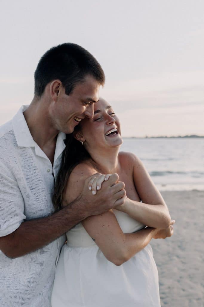parents to be are smiling and laughing. they are cuddling close. sunset maternity photo shoot at the beach. spring maternity photo session. Ewa Jones Photography