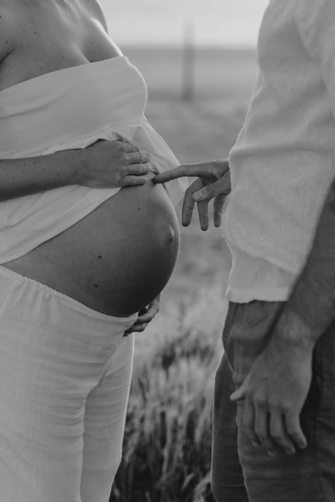 Dad is touching baby bump. black and white photograph. Hampshire photographer. Love and connection. Ewa Jones Photography