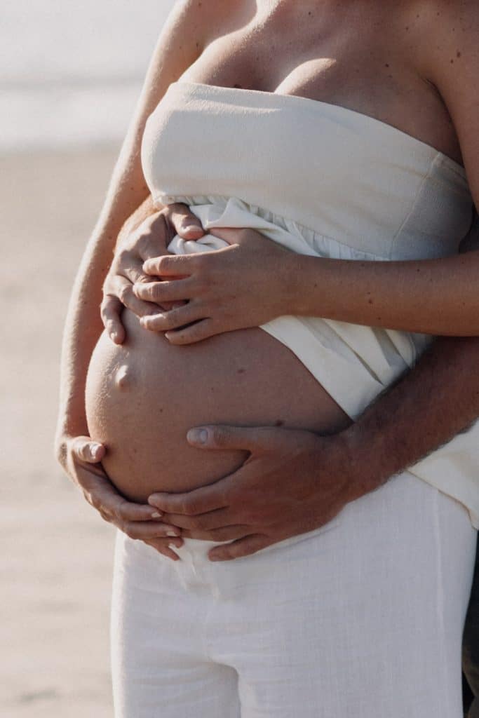 Close up baby bump. parents are holding baby bump. Maternity shoot at the beach. Natural maternity photo session. Hampshire photographer. Ewa Jones Photography