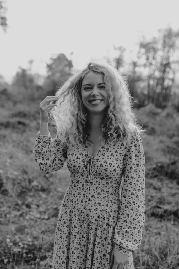 Black and white image of female looking at the photographer and smiling. female natural photo session. Outside shoot. Hampshire photographer. Ewa Jones Photography