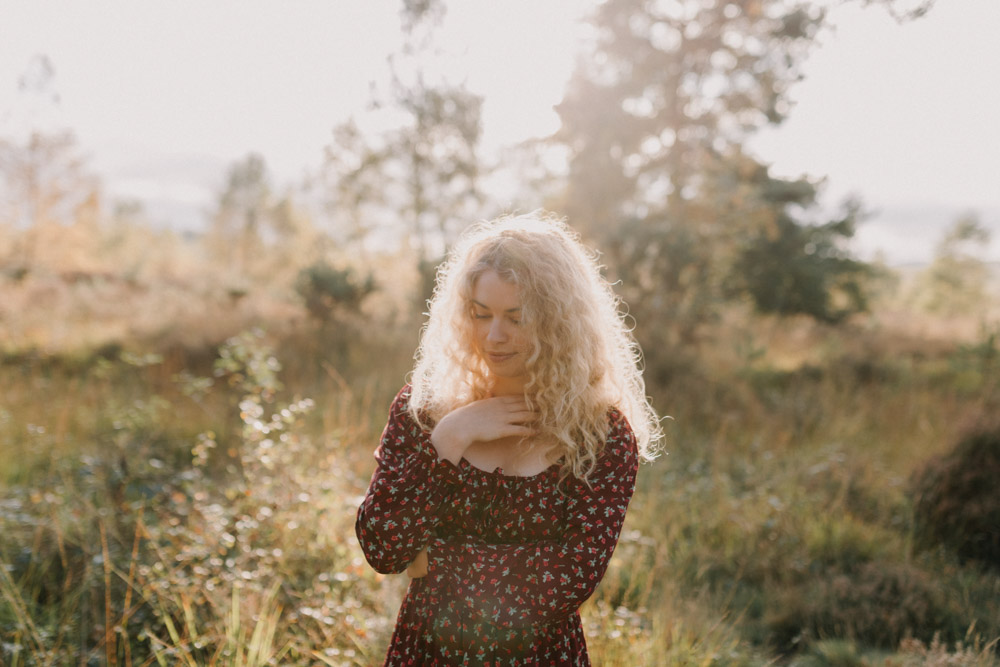 woman is wearing red dress and standing in the field. she has her eyes closed. lovely natural photo session outside. Women photoshoot. hampshire female photographer. Ewa Jones Photography