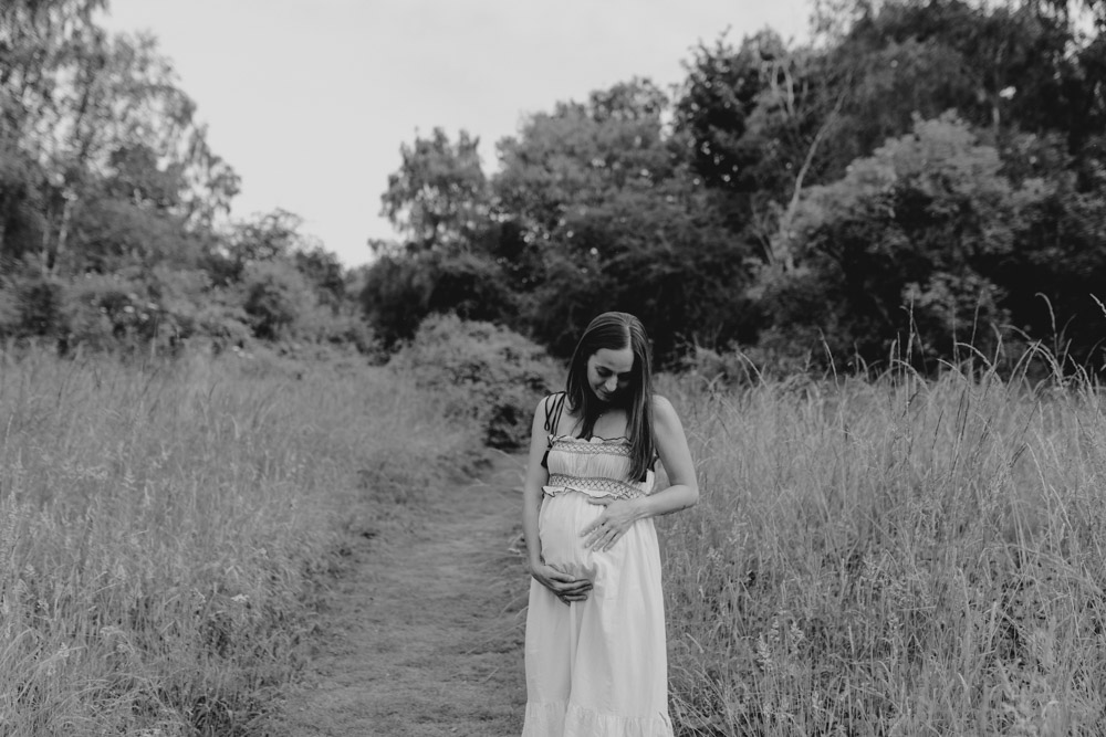 Mum is standing and looking at the bump. maternity photo shoot. Natural maternity session. Hampshire photographer. Ewa Jones Photography