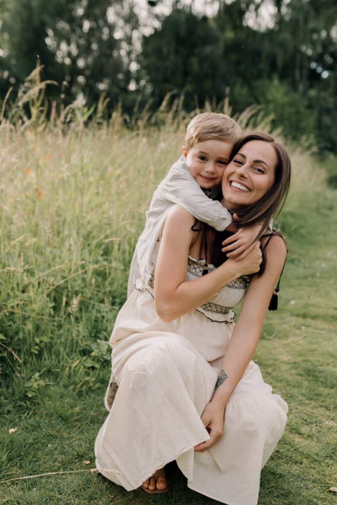 Baby boy is cuddling mum and smiling. Lovely natural family session. How to prepare for a family session. Maternity and family shoot outside. Hampshire photographer. Hampshire photo session. Ewa Jones Photography