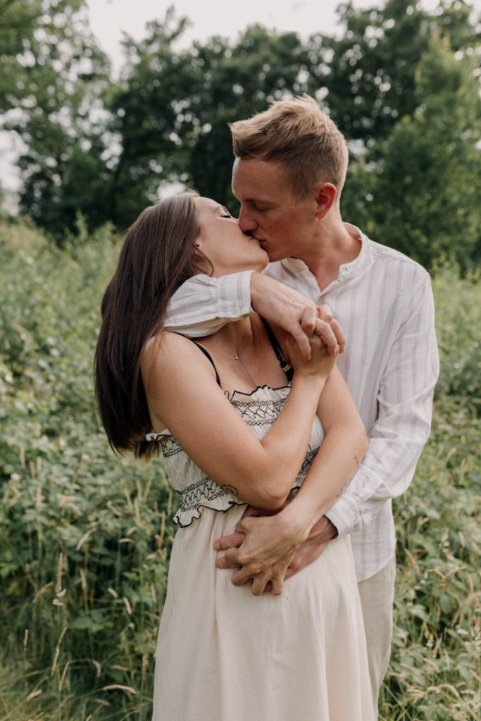 Mum and dad are cuddling and giving each other a kiss. Maternity shoot. Maternity photographer in Hampshire. Ewa Jones Photographer