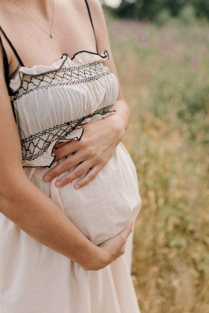 close up of mum cuddling baby bump. natural outdoor maternity photoshoot. Basingstoke photographer. Hampshire outdoor photo shoot. Ewa Jones Photographer
