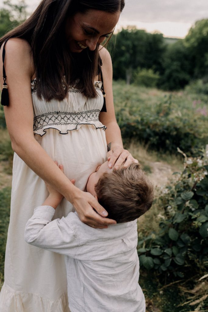 Boy is holding and kissing baby bump. mum is lovingly looking down at her son. Hampshire maternity session. Ewa Jones photoshoot.