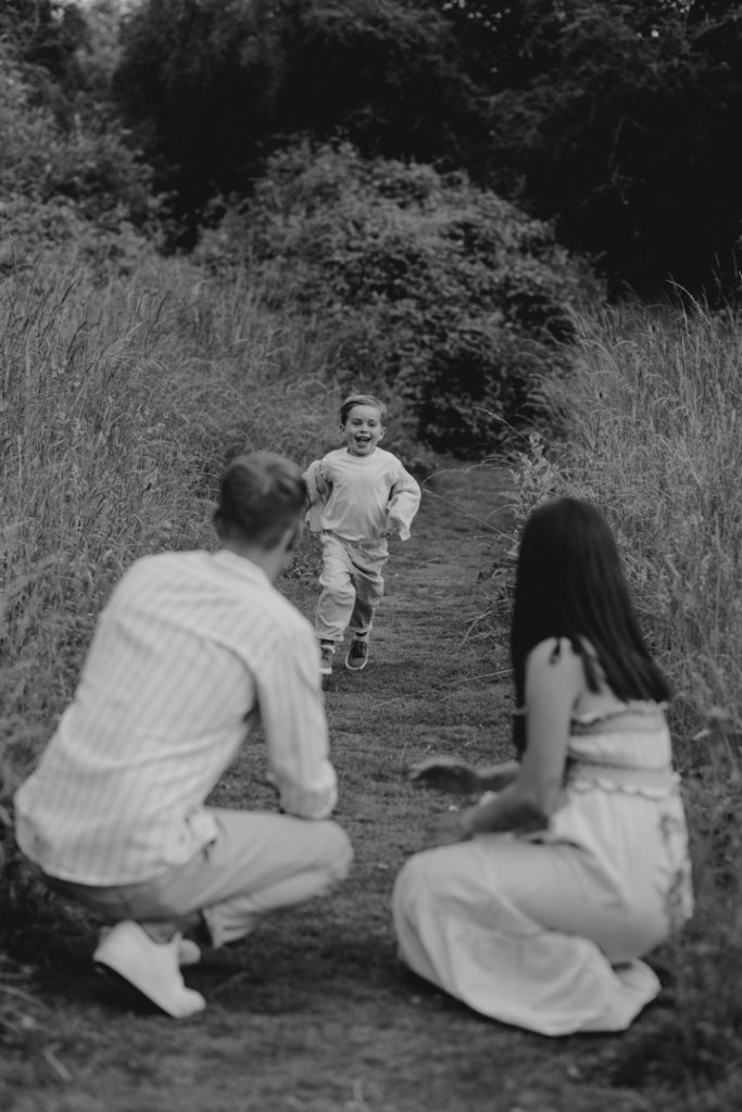 Little boy is running towards mum and dad. Happy and natural family session outdoors. Family photographer in Hampshire. Hampshire photographer. Ewa Jones Photography