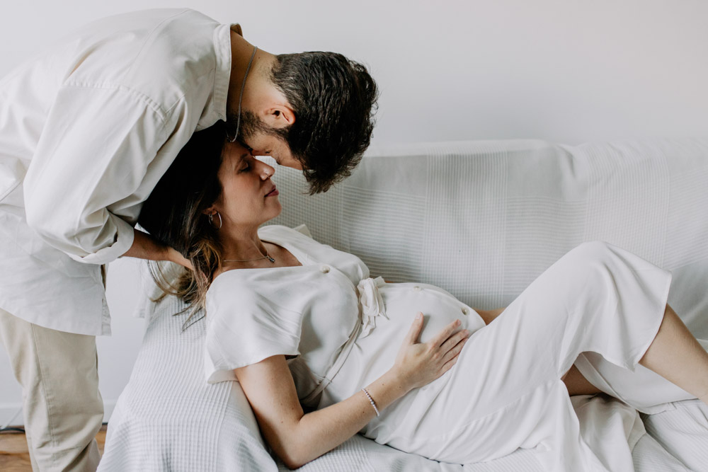 Dad to be is kissing his wife. Mum to be is holding baby bump. Natural maternity portraits. Hampshire photographer. Ewa Jones photographer